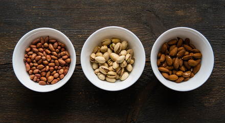 Pistachio, peanut and almond in a small plates which standing on a black table. Nuts is a healthy vegetarian protein and nutritious food.