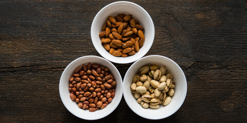 Pistachio, peanut and almond in a small plates which standing on a black table. Nuts is a healthy vegetarian protein and nutritious food.