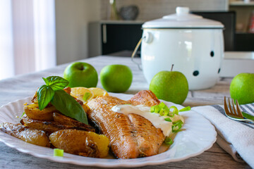 fried salmon fillet with roasted potatoes and tartar sauce on a plate
