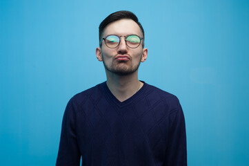 Portrait of young positive guy wearing casual clothes posing on blue background.