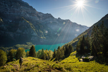 Woman hiking in the Swiss alps, view over mountain lake and mountain face in the background.