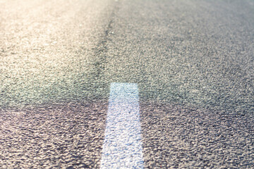 Background texture of asphalt with a white dividing strip of the road. Close-up photo.