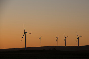 A wind farm during sunset. Turbines generating electricity. Green energy