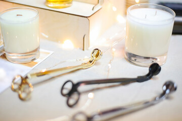 Wick golden, black, silver metal scissors for extinguishing white aroma candles in glass cups are...