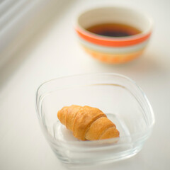 croissant in glass bowl and tea on the windowsill.