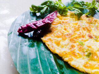 Egg Omelette with coriander leaves and red chillies in a banana leaf.