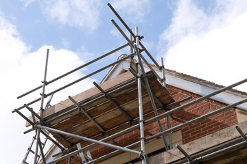 Modern house roof construction with scaffold pole platform. New build domestic building against...