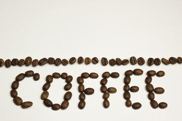 The word COFFEE is laid out on a white background with coffee beans. Above it is a strip of coffee beans