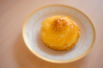 creamy curd cake in a white saucer on a wooden table.