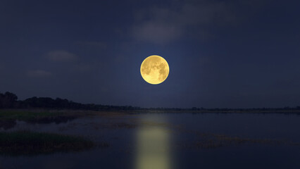 Big full moon in blue sky over the lake in the evening