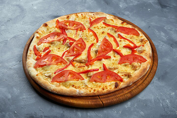 Baked italian pizza with tomatoes, bell pepper, chicken and cheese on a wooden tray on a gray background