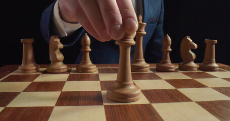 Businessman playing chess game moving white queen on board