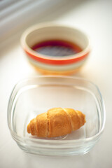 croissant in glass bowl and tea on the windowsill.