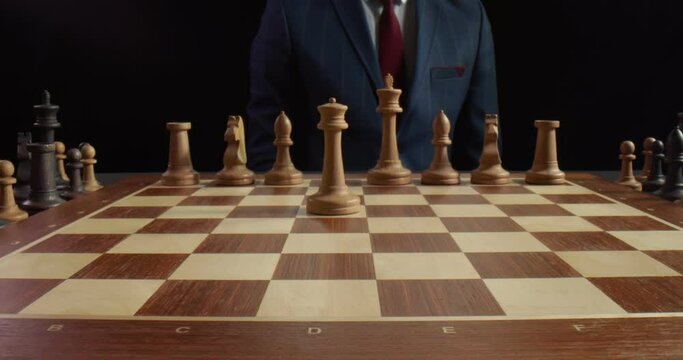 Close up of businessman hand moving white queen piece on chess board