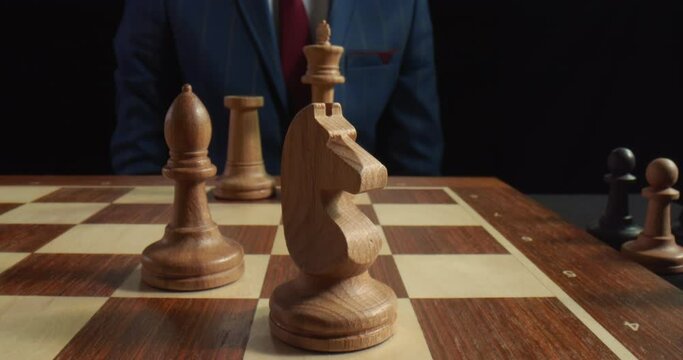 Close up of grandmaster hand moving white knight on board during chess game