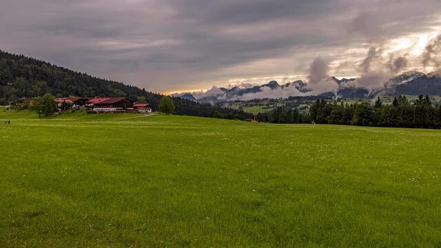 4k timelapse of a dramatic sunset with fast moving clouds in Reit im Winkl in the bavarian alps during a cloudy and windy day in summer.