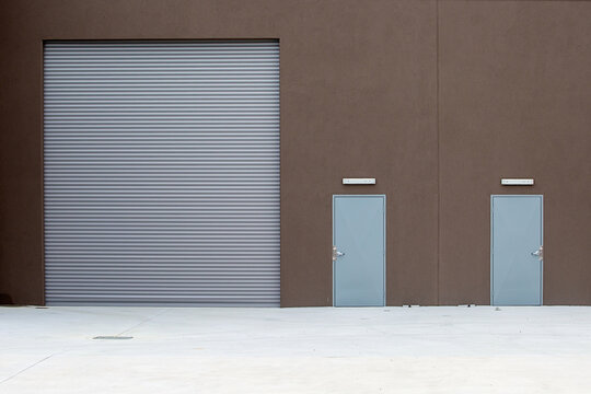 Grey Warehouse Roller Door With Brown Wall And Two Doorways