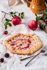 Homemade galette with peaches on light background