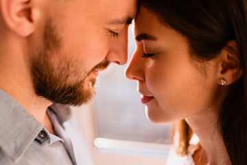 Portrait loving couples enjoying each other company with window in background with sunlight reflection on their faces