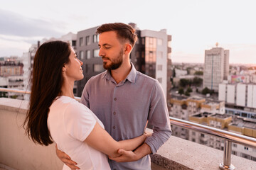 Close up portrait, man and woman smiling to each other on sunset with city in background. Couple romantic intimate moments