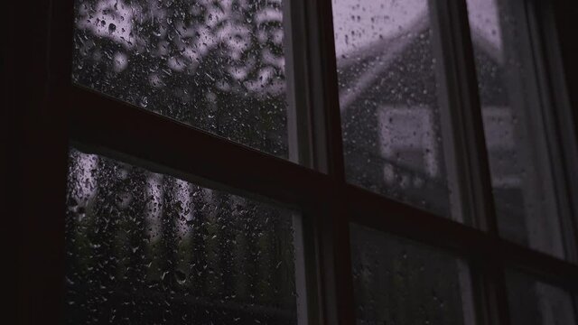 Close up of water droplets sliding on transparent glass, raindrops strike a window