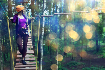 Naklejka na ściany i meble extreme vacation, girl in a yellow helmet rope park active holidays in the forest