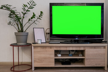 Mockup, green screen TV on the bedside table next to the potted plant