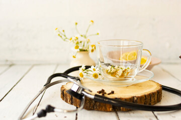 Decoction of chamomile, dried flower in flower tea and a phonendoscope, sliced lemon on a white...