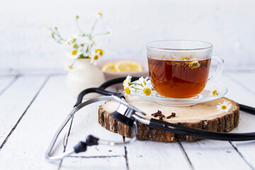 Decoction of chamomile, dried flower in flower tea and a phonendoscope, sliced lemon on a white...