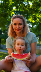 Little baby piece of watermelon and her Mom in summer park