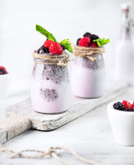 Berry milkshake  in glass bottles on white wooden cutboard on white.