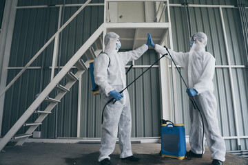 Team in virus protective suite and mask encourage and hands together to cleaning covid19 infected area , Virus disinfection concept