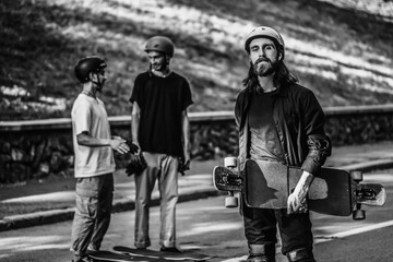 A group of guys ride longboards. Black and white portrait of a skateboarder.