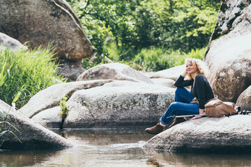 Woman with backpack having rest while hiking in the river valley