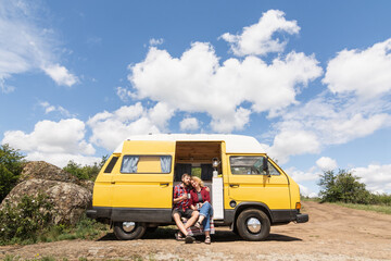 Young couple travelling by yellow campervan though the countryside