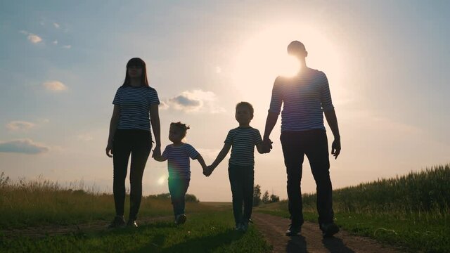 Happy family. Lovely couple with kids strolling at sunset in the evening around the field. The concept is the teamwork of hiking, active lifestyle, parenting.