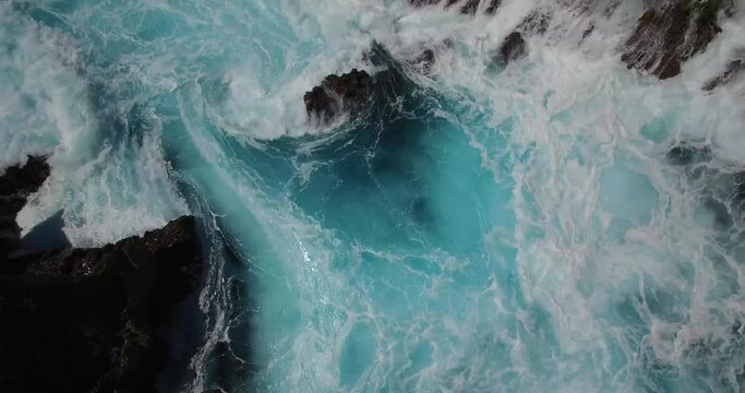 BEAUTIFUL CINEMATIC 4K AERIAL OF DEEP BLUE WAVES CRASHING AGAINST ROCK CLIFF