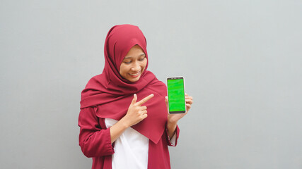 Asian woman pointing to the cellphone with the green screen