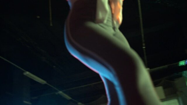 Young girl roller-skating around obstacles in dark studio. Teenager figure skating in colourful spotlight with friend recording on camera represent nightlife culture. Concept of lifestyle, extreme.