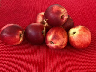 Fresh red nectarine on red cloth napkin on table. Selective focus