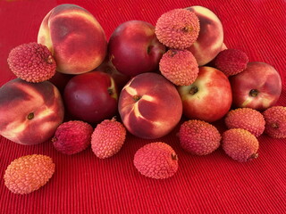Mix fruit: fresh red peaches, nectarine and lychee on red cloth napkin