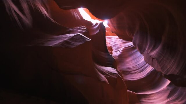 Low angle view looking up on light sky at upper Antelope slot canyon with red layers of wave shape rock sandstone in Page, Arizona panning handheld