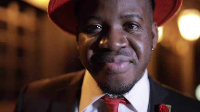 Elegant confident African businessman clothe red hat in the night city closeup