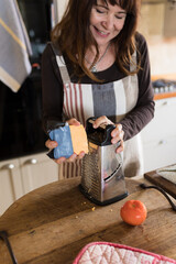 Woman grating cheese in kitchen