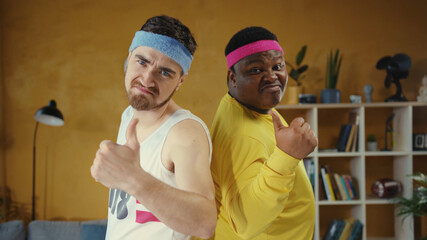 Diverse male couple of unfit weak weird men wearing sportswear, posing back to back looking very self-confident at camera. Sport humor and fun concept.