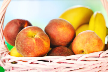 Fresh peaches and bananas. Wicker basket with summer fruits. Healthy food background.