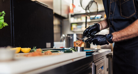 Professional chef in restaurant kitchen preparing delicious meal with meat and vegetables.