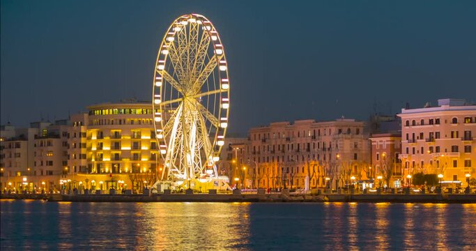 4K time lapse panoramic Night view of Illuminated giant Ferris wheel on the waterfront of Bari, region of Apulia, Italy. Puglia. Panorama