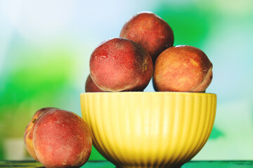 Summer harvest of peaches. Bowl of fresh peaches on natural green background.