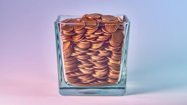The glass is filled with small coins. Stop motion.